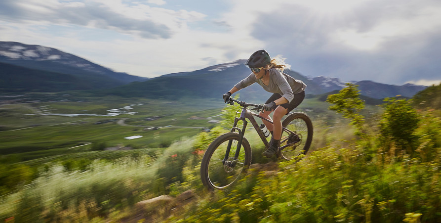 Kvinna som cyklar mountinbike i fjällmiljö.